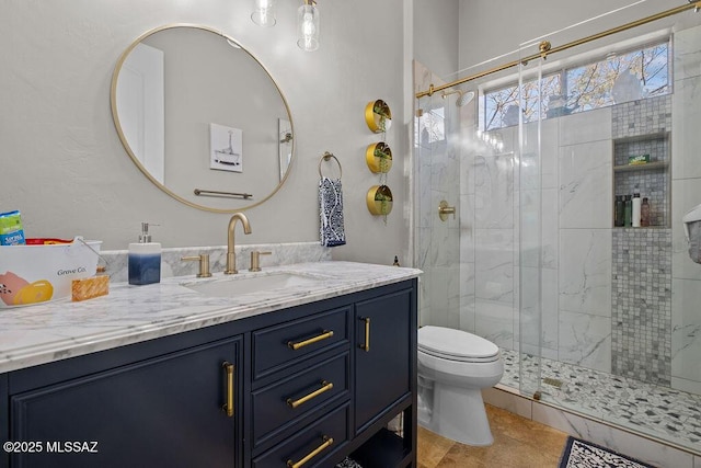 bathroom featuring toilet, a shower stall, and vanity