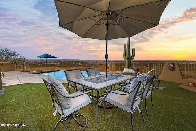 patio terrace at dusk with a fenced in pool and a lawn