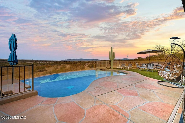 pool at dusk with a patio area and an outdoor pool