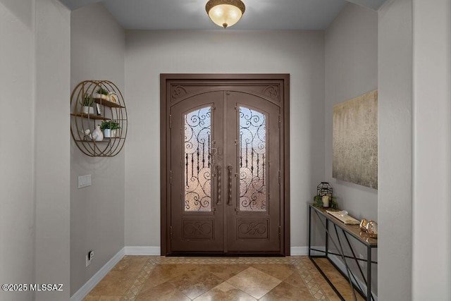 foyer entrance featuring baseboards and french doors