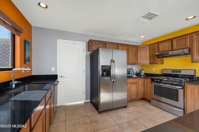 kitchen featuring sink, appliances with stainless steel finishes, dark stone counters, and light tile patterned flooring