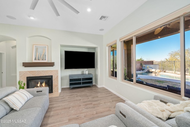 living room with ceiling fan, light hardwood / wood-style flooring, and a tile fireplace