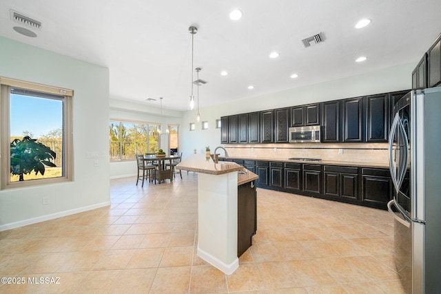 kitchen featuring stainless steel appliances, decorative backsplash, light tile patterned flooring, hanging light fixtures, and sink