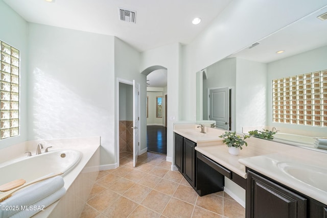 bathroom with vanity, plenty of natural light, and a relaxing tiled tub