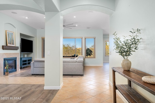 living room with ceiling fan, a fireplace, and light hardwood / wood-style flooring