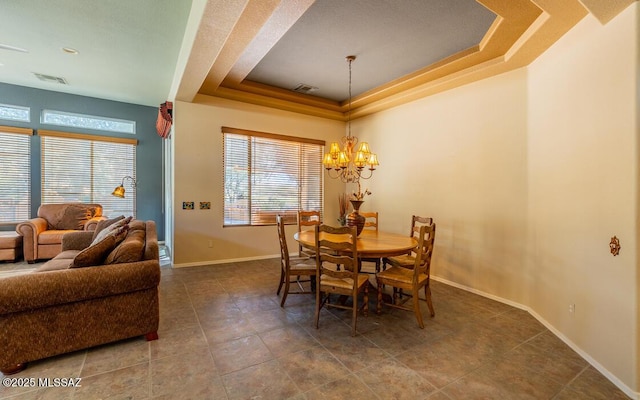 dining space featuring a tray ceiling and a chandelier