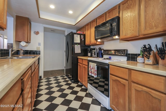 kitchen featuring black appliances, sink, and a tray ceiling