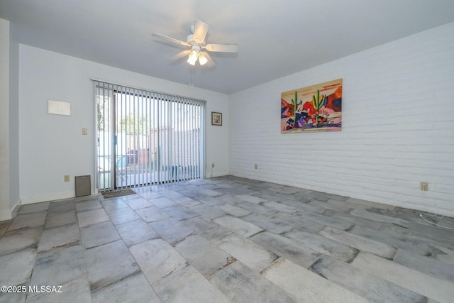 unfurnished room featuring brick wall and ceiling fan