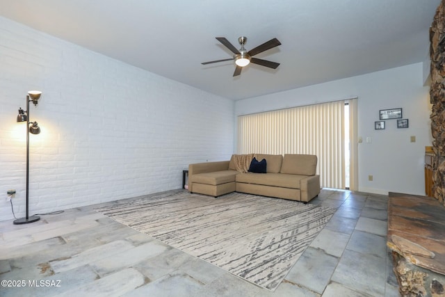 living room featuring ceiling fan and brick wall