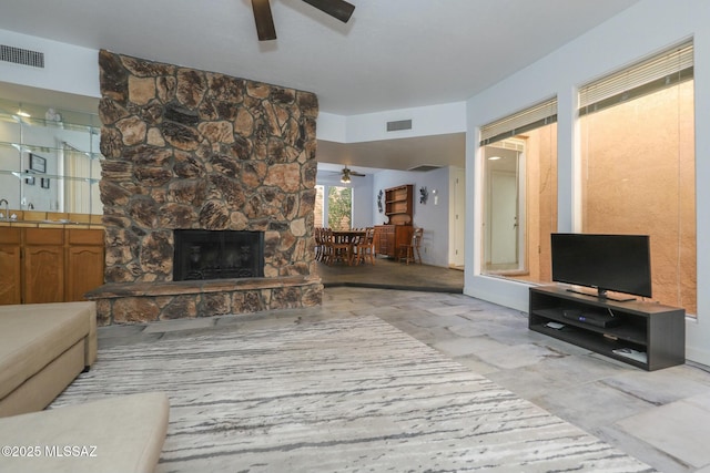 living room with ceiling fan and a stone fireplace