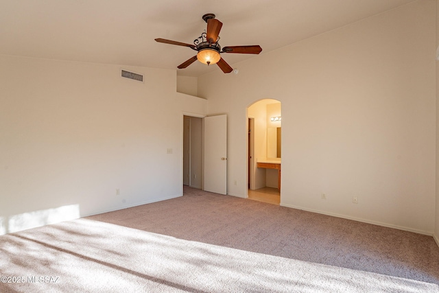 unfurnished bedroom with ensuite bath, high vaulted ceiling, ceiling fan, and light carpet