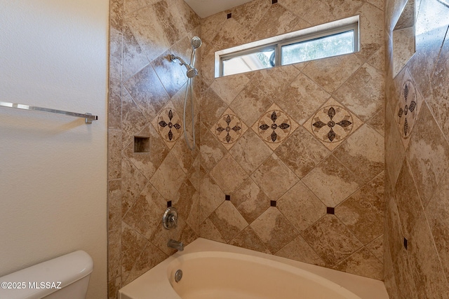 bathroom with toilet and tiled shower / bath