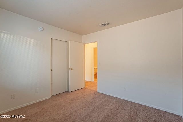 unfurnished bedroom with a closet and light carpet