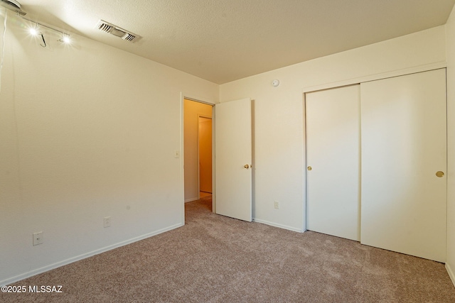 unfurnished bedroom with a closet and light colored carpet