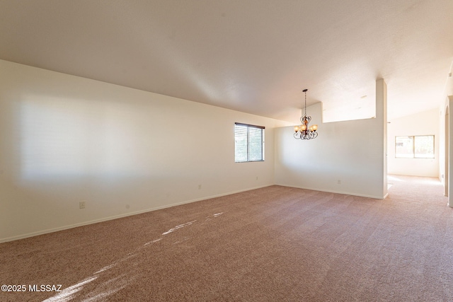 empty room featuring lofted ceiling, carpet floors, and a chandelier