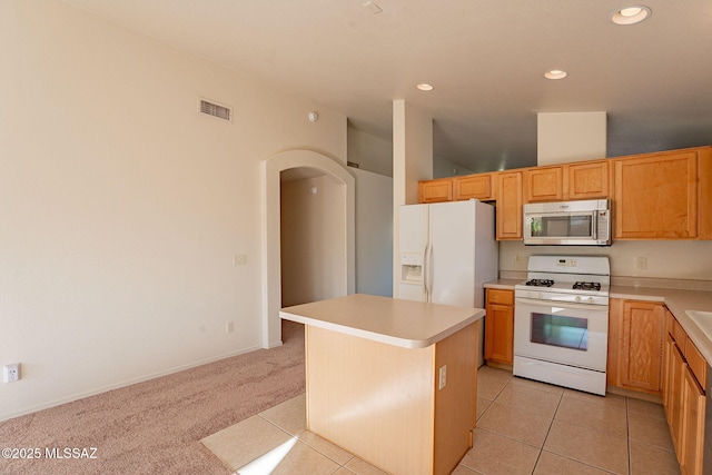 kitchen with white appliances, lofted ceiling, light tile patterned floors, and a center island