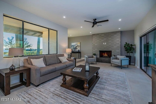 living room featuring ceiling fan and a stone fireplace