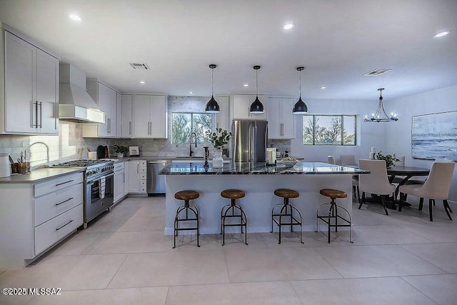 kitchen featuring custom exhaust hood, high quality appliances, backsplash, white cabinetry, and a center island