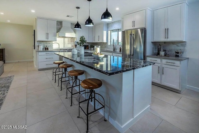 kitchen with custom exhaust hood, white cabinets, a center island, decorative backsplash, and stainless steel appliances