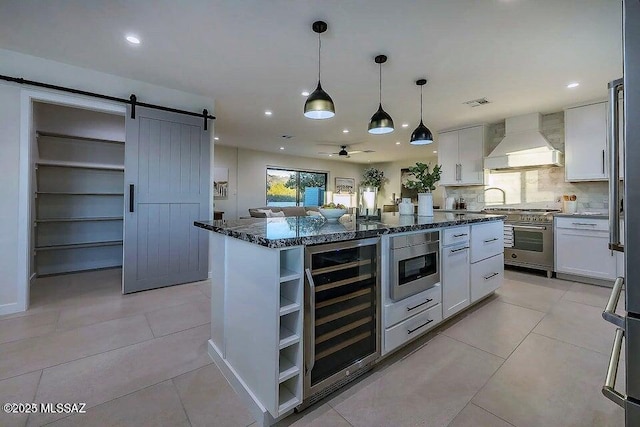 kitchen with custom exhaust hood, white cabinets, a center island, and wine cooler