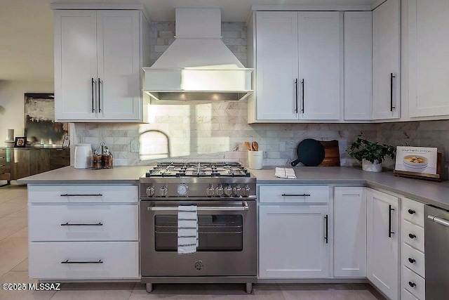 kitchen featuring backsplash, white cabinetry, stainless steel appliances, and custom range hood