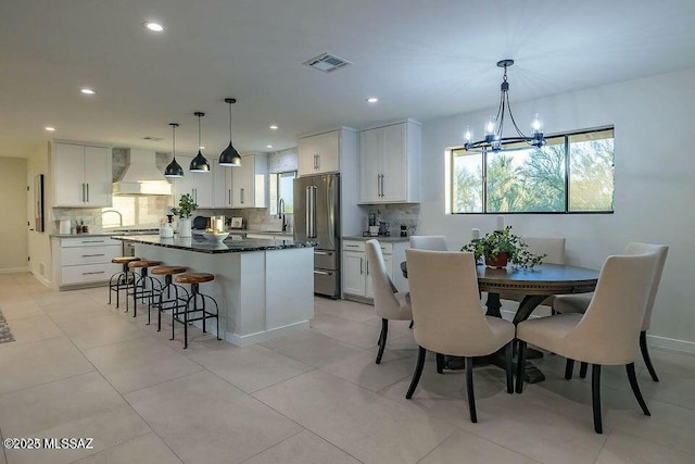 kitchen featuring premium range hood, a kitchen island, white cabinetry, and high end fridge