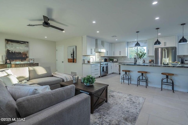 living room with sink, light tile patterned floors, and ceiling fan