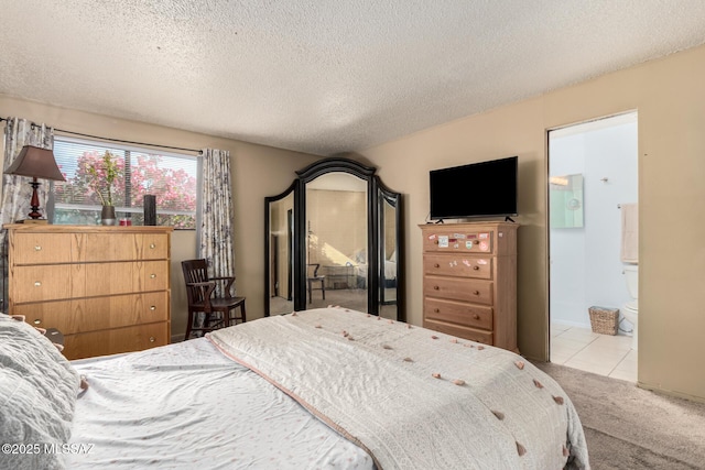 bedroom featuring ensuite bathroom, light colored carpet, and a textured ceiling