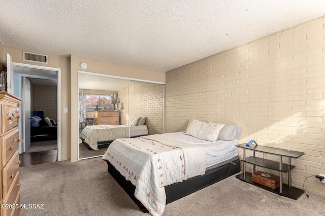 carpeted bedroom featuring a textured ceiling, a closet, and brick wall