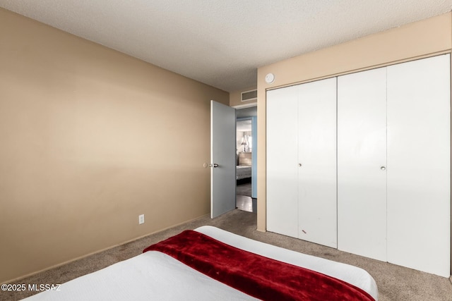 carpeted bedroom featuring a textured ceiling and a closet