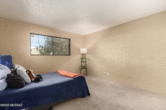 carpeted bedroom featuring a textured ceiling and brick wall