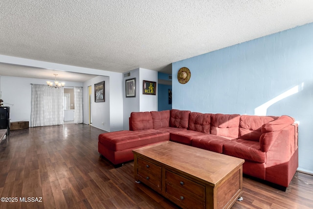 living room with a textured ceiling, a chandelier, and dark wood-type flooring