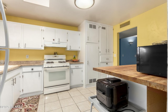 kitchen featuring light tile patterned flooring, white range with gas cooktop, and white cabinetry