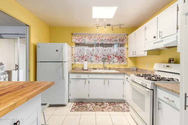 kitchen featuring white appliances, a skylight, white cabinets, and sink