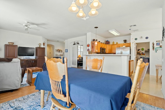 dining space featuring ceiling fan with notable chandelier and light wood-type flooring