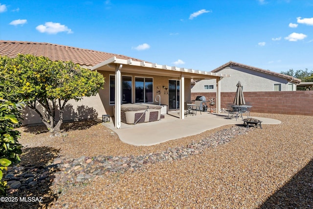 back of property with a hot tub, a patio, and a fire pit