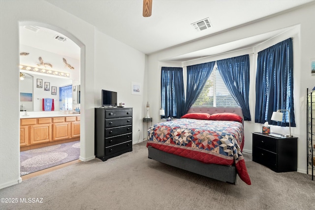bedroom with ensuite bathroom, carpet, and ceiling fan