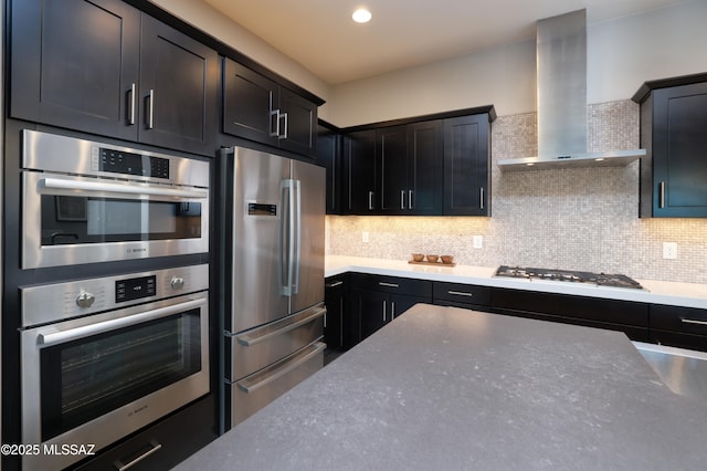 kitchen with tasteful backsplash, appliances with stainless steel finishes, and wall chimney exhaust hood