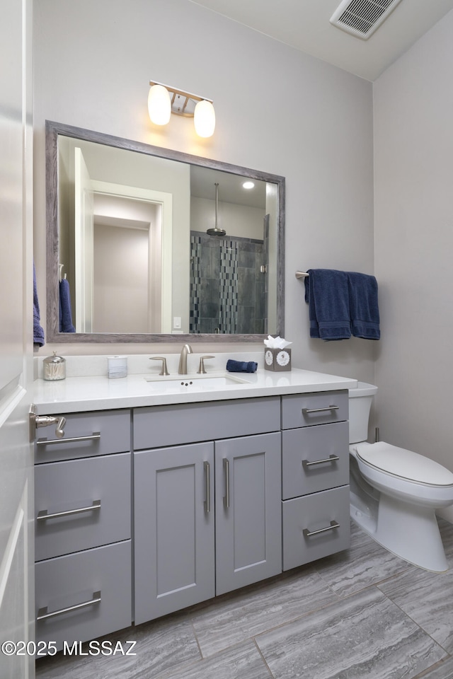 bathroom with an enclosed shower, vanity, and toilet