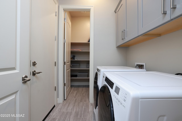 laundry room with separate washer and dryer and cabinets