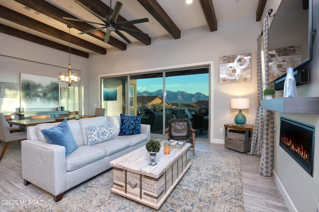 living room featuring wood-type flooring, beamed ceiling, and ceiling fan with notable chandelier