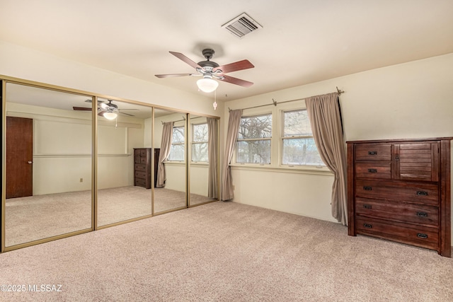 unfurnished bedroom featuring light colored carpet, ceiling fan, and a closet