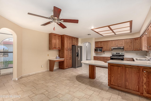 kitchen featuring appliances with stainless steel finishes, a baseboard radiator, sink, ceiling fan, and kitchen peninsula