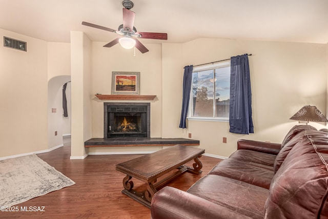 living room featuring dark hardwood / wood-style flooring, a tile fireplace, ceiling fan, and lofted ceiling