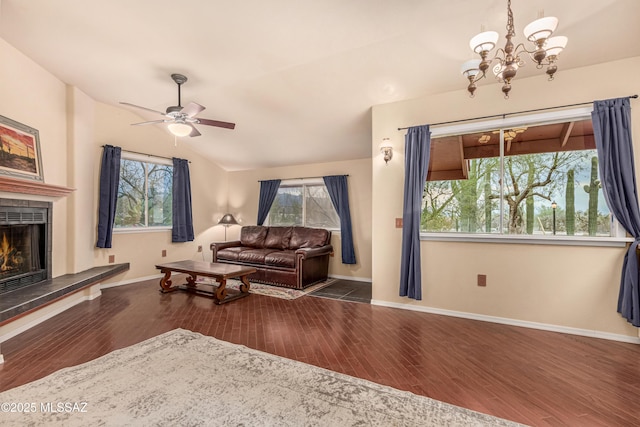 living room with vaulted ceiling, dark hardwood / wood-style floors, ceiling fan with notable chandelier, and a fireplace