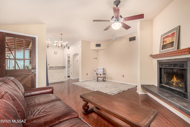 living room with dark hardwood / wood-style floors, ceiling fan with notable chandelier, and a tile fireplace