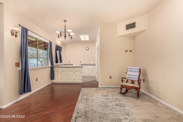 sitting room with vaulted ceiling, dark wood-type flooring, and an inviting chandelier