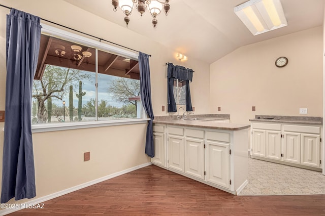 kitchen featuring white cabinetry, sink, vaulted ceiling, and wood-type flooring