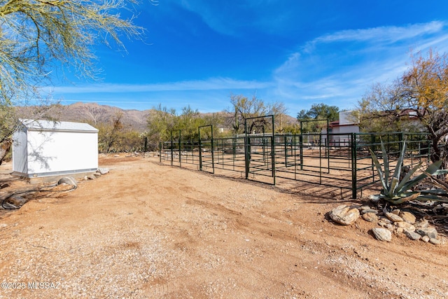 view of yard with a mountain view, an outbuilding, and a rural view