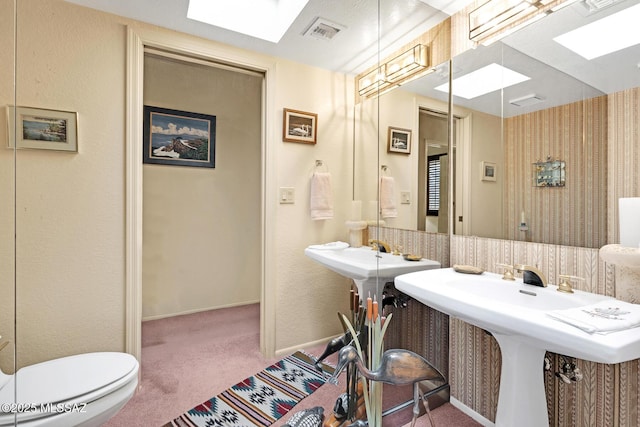 bathroom with sink, a skylight, backsplash, and toilet